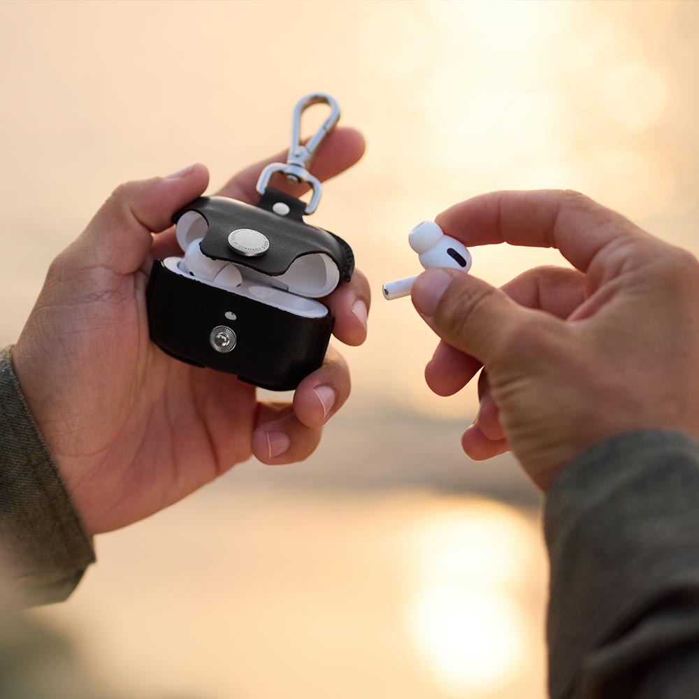 Zwei Hände halten ein geöffnetes Airpods Case aus Leder in den Händen