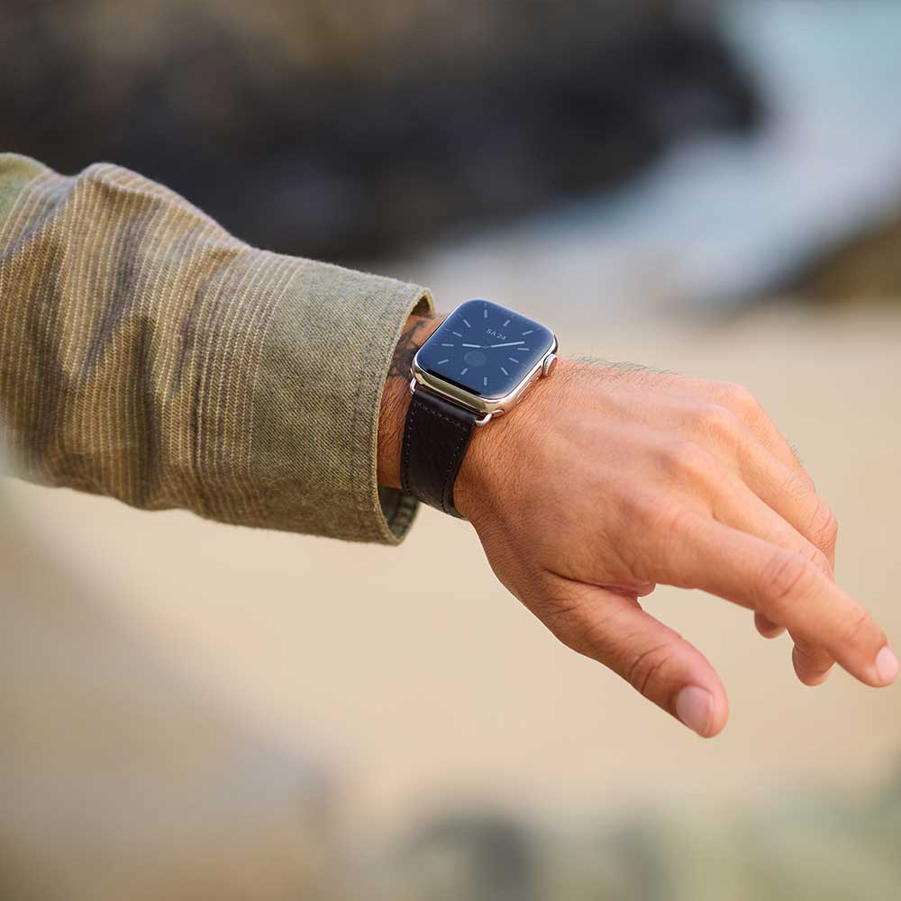 Ein Mann trägt eine Apple Watch mit schwarzem Lederarmband von Goodwilhelm am Handgelenk