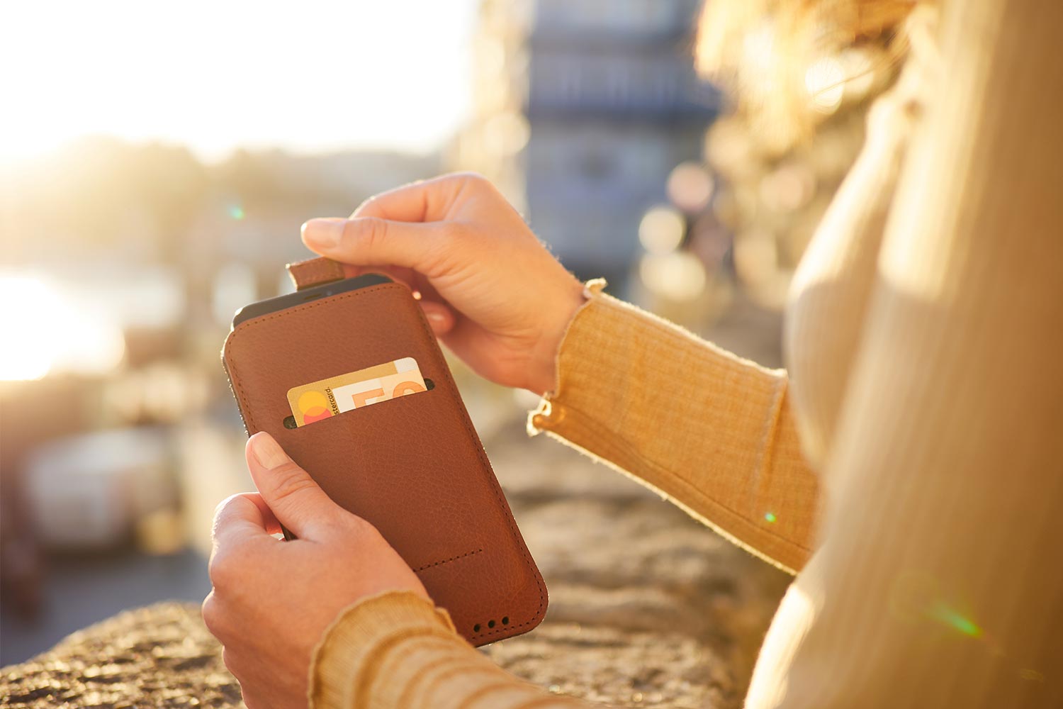 Eine Frau hält ein iPhone Leder Case in der Hand und zieht das Gerät raus