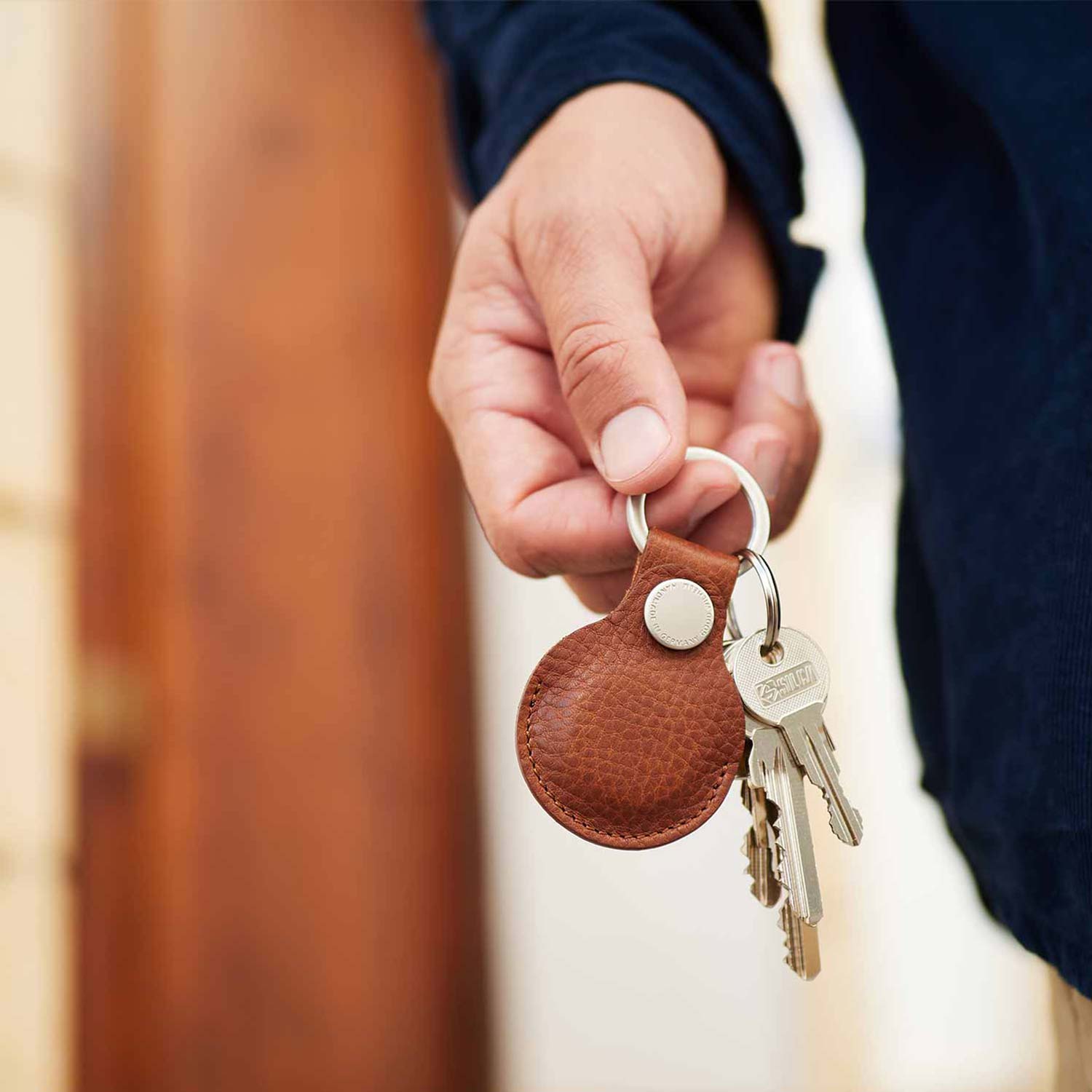 Eine Hand hält einen Airtag Schlüsselanhänger aus Leder in der Hand